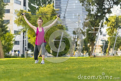 Young sportswoman performing exercises on the grass in a city Stock Photo
