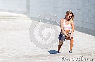Young sportswoman stretching and preparing to run. listens to the music on mobile app. Stock Photo