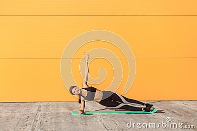 Young sporty attractive woman practicing yoga, doing vasisthasana exercise, side plank pose on elbows Stock Photo