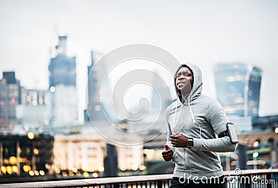 Young sporty black man runner running on the bridge outside in a city. Stock Photo