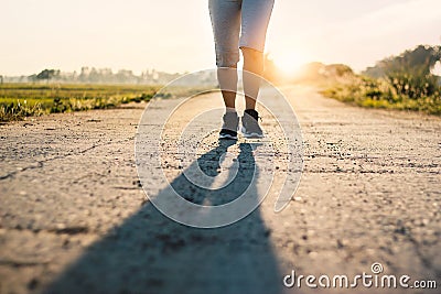 Young sporty fitness woman trail running on rural road in summer Stock Photo