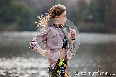 Young sporty girl jogging in city park at autumn day. Stock Photo