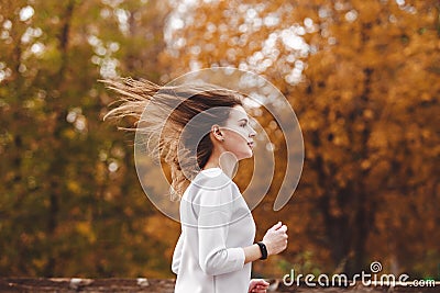 Young sporty girl jogging in city park at autumn day. Stock Photo