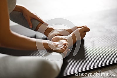 Young sporty woman doing yoga stretching exercise sitting in gym near bright windows Stock Photo