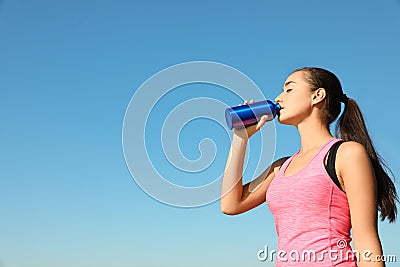 Young sporty woman drinking from water bottle outdoors on sunny day Stock Photo