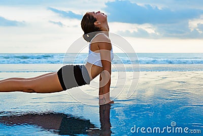 Young sporty woman stretching on sunset beach Stock Photo