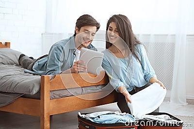 Young spouses packing clothes and booking tickets Stock Photo