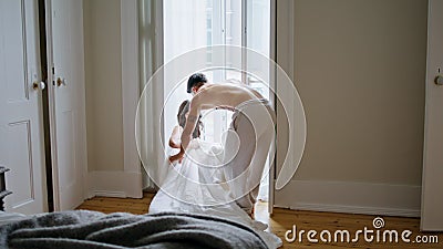 Young spouses sitting at window interior. Love pair enjoying morning at bedroom Stock Photo