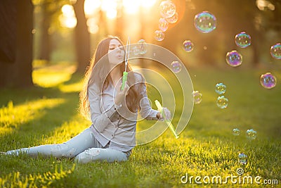 Young spring fashion casual woman blow bubbles in the sunset in Stock Photo