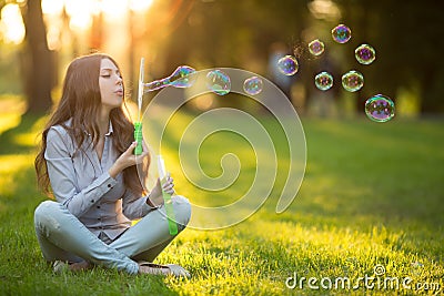 Young spring fashion casual woman blow bubbles in the sunset in Stock Photo