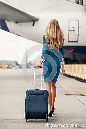 Young stewardess with suitcase on aircraft parking Stock Photo