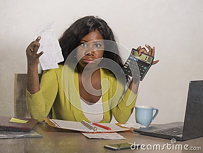 Young stressed and overwhelmed black African American woman doing domestic accounting with calculator feeling upset and angry Stock Photo