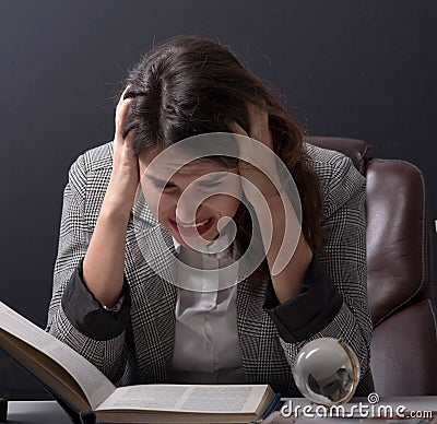 Young stressed student girl studying pile of books on library desk preparing test or exam in stress feeling Stock Photo