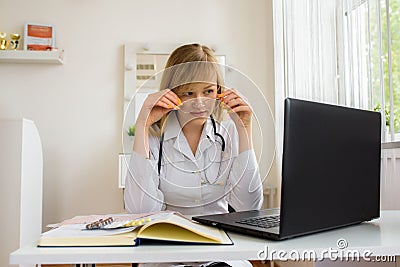 young stressed woman doctor sitting in modern office.tired doctor at the computer. online consultation. Stock Photo