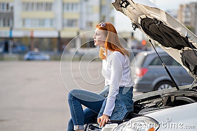 Young stressed woman driver near broken car with popped hood waiting for assistance Stock Photo