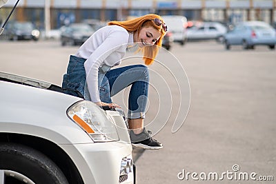 Young stressed woman driver near broken car with popped hood waiting for assistance Stock Photo