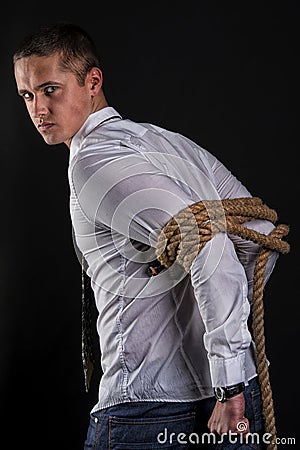 Young beautiful man tied up with rope stands sideways Stock Photo