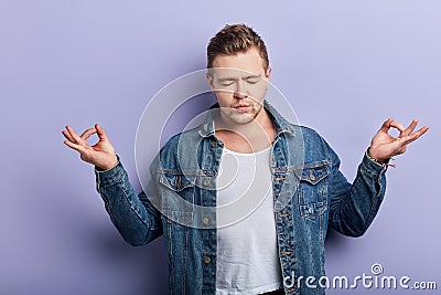 Young strong muscular bearded man wearing denim jacket practising yoga Stock Photo