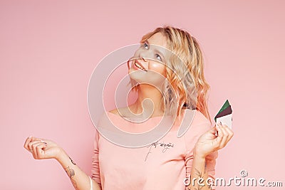 Young student hipster woman with colored hairs and tattoo holding credit cards. Concept purchases. On the pink Stock Photo