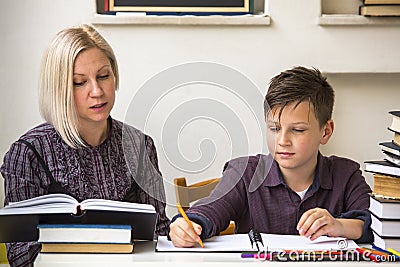 Young student learns at home with a his mom tutor. Helping. Stock Photo