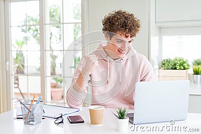Young student man working and studying using computer laptop screaming proud and celebrating victory and success very excited, Stock Photo