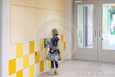 A young student puts her school supplies in a locker on a locker wall Editorial Stock Photo