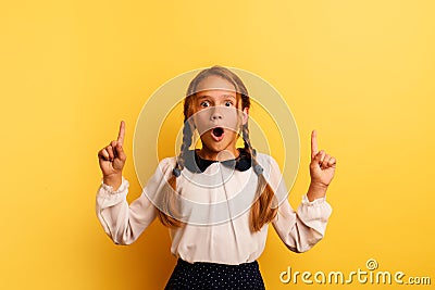 Young student is with shocked expression and indicates something. Yellow background Stock Photo