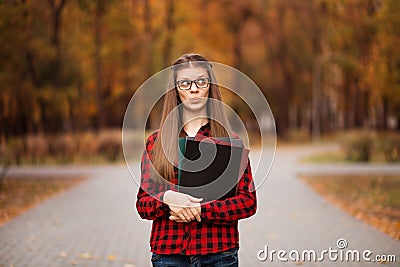 Young student with surprised face looks out of folder in red checkered shirt. Portrait of clever young woman Stock Photo