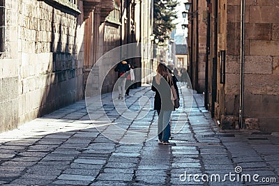 Young student walking by old street of Salamanca near University Editorial Stock Photo