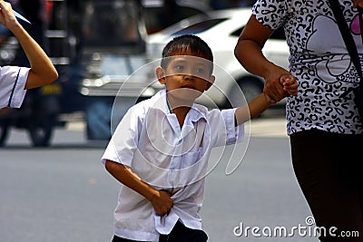 A young student walks with his mother going to school. Editorial Stock Photo