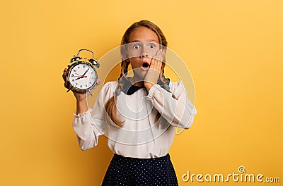 Young student is worried because it is late to go school. yellow background Stock Photo