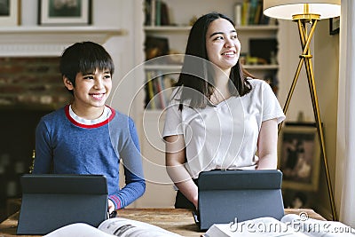 Two Siblings Home Schooling During the Corona Virus Inside Home Smiling Stock Photo