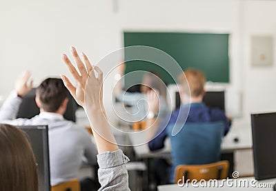 Young students raising hands in a classroom Stock Photo