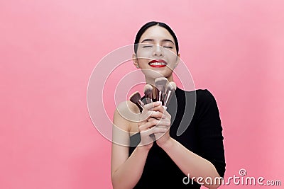 Young Stylish Asian woman carrying makeup brushes on hand with c Stock Photo