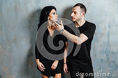 Young stylish beautiful gorgeous couple, against the gray wall loft in the studio or at home. Stock Photo