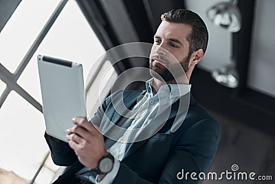 Young stylish businessman leader indoors at office using digital Stock Photo