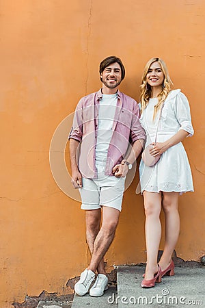 young stylish couple holding hands while standing against city Stock Photo