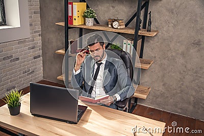 Young stylish handsome businessman working in the office at his desk making some notes thinking Stock Photo