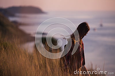 Young stylish hipster girl enjoy sunset on viewpoint. Travel woman with backpack Stock Photo