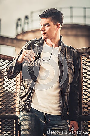 Young stylish man model posing in leather jacket and sunglasses. Stock Photo