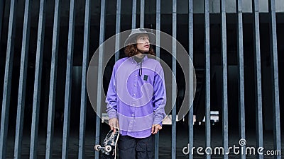 Young stylish man staying outdoor. Skater waiting for workout with longboard. Stock Photo