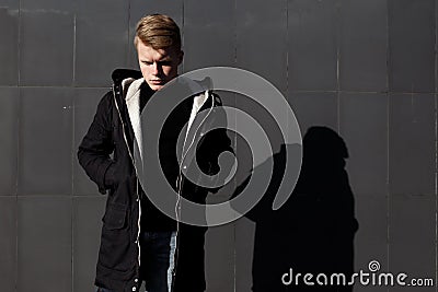 Young stylish redhead man in trendy outfit posing against urban background Stock Photo