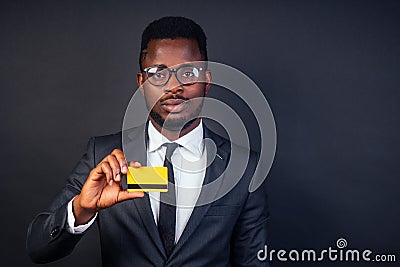 Young successful businessman credit broker in a stylish black classic suit and in cool glasses holding a yellow plastic Stock Photo