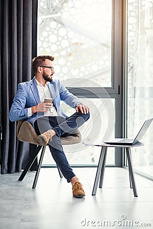 Successful businessman have a break resting and drinks fragrant coffee in modern office room. Successful young Stock Photo