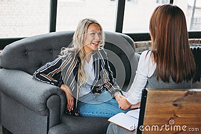 Young successful women colleagues talk to each other, coaching or psychotherapy in modern loft office Stock Photo