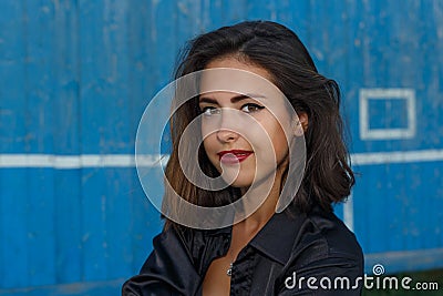 Young suntanned woman in a short top and shirt with beautiful modern make-up and hair posing against blue wooden wall Stock Photo