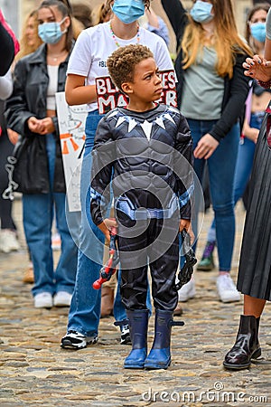 A young Superhero at a Black Lives Matter protest with white protesters wearing PPE masks in the background Editorial Stock Photo