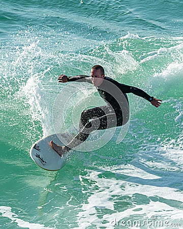 Young surfer enjoys the waves confronting the surf by surfing the rougher waters after a morning rain storm Editorial Stock Photo