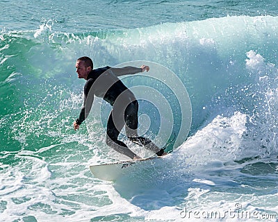 Young surfer enjoys the waves confronting the surf by surfing the rougher waters after a morning rain storm Editorial Stock Photo