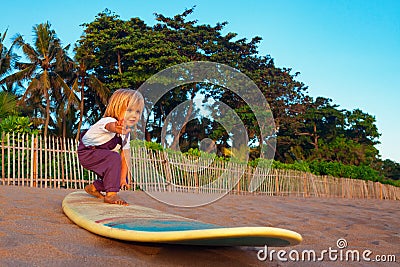 Young surfer stand on surfboard with fun on sunset beach Stock Photo